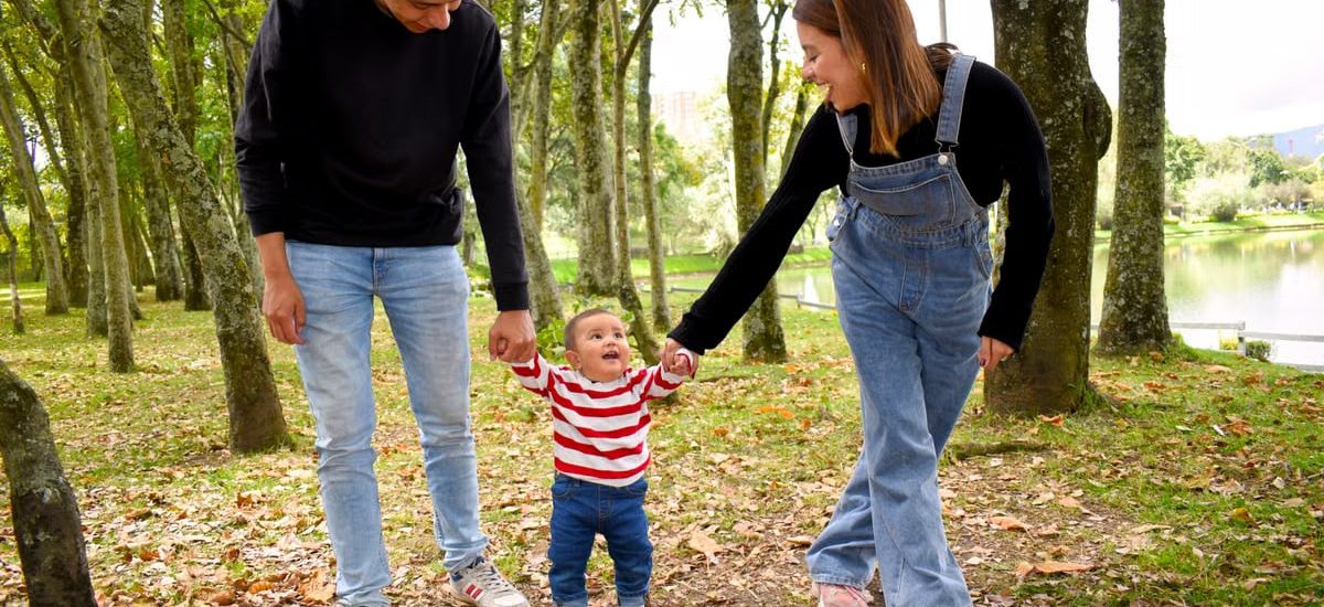 A joyful family enjoys a walk under lush green trees in the park.