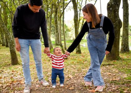 A joyful family enjoys a walk under lush green trees in the park.